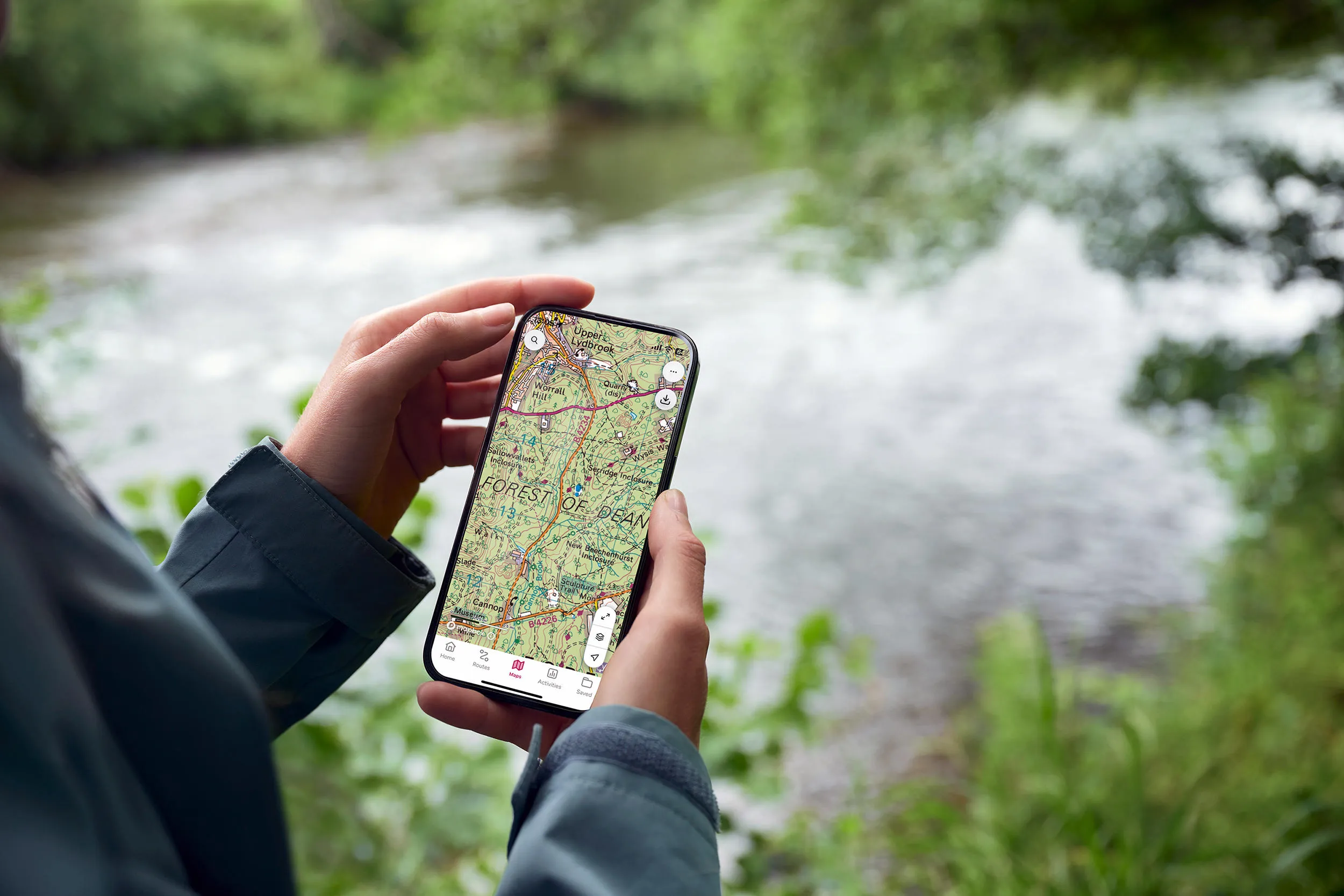 Individual by a river holding a phone using OS Maps